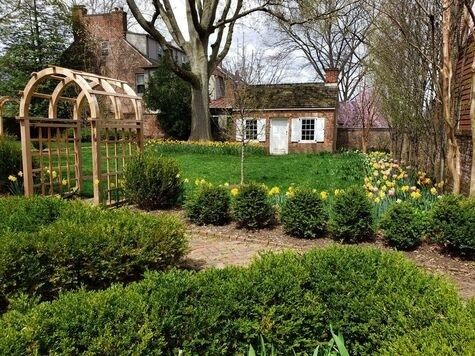 Historischer Garten mit Buchsbaumhecken, Laubengang und Frühlingsblumen