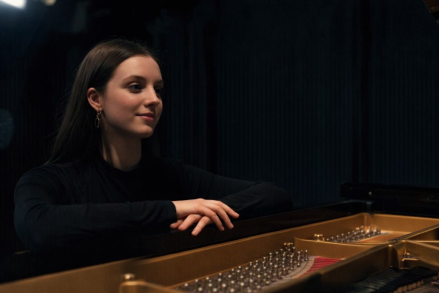 Eine junge Frau blickt lächelnd über das geöffnete Innenleben eines Flügels.